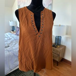 Rust colored, sleeveless blouse with metal accents.